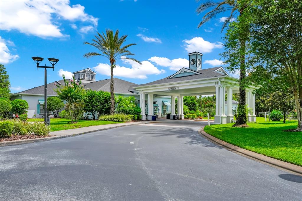 A paved driveway leads to the covered entrance of a building with a clock tower — 7503 ATLANTIS WAY UNIT J108, KISSIMMEE, FL
