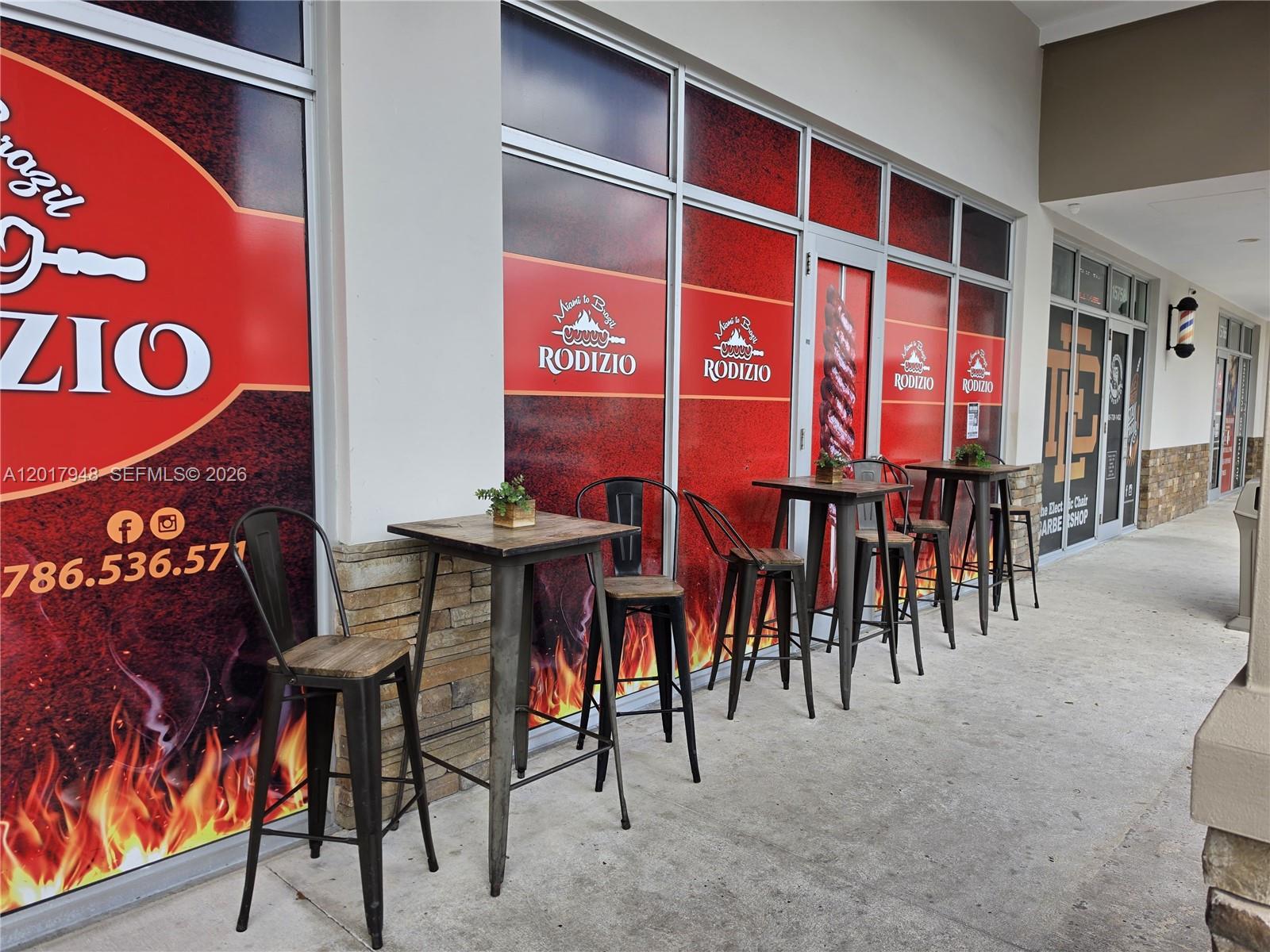The exterior of a restaurant features window decals, outdoor tables, and high-top chairs — 15750 SW 56 ST, Miami FL 33185, MIAMI, FL