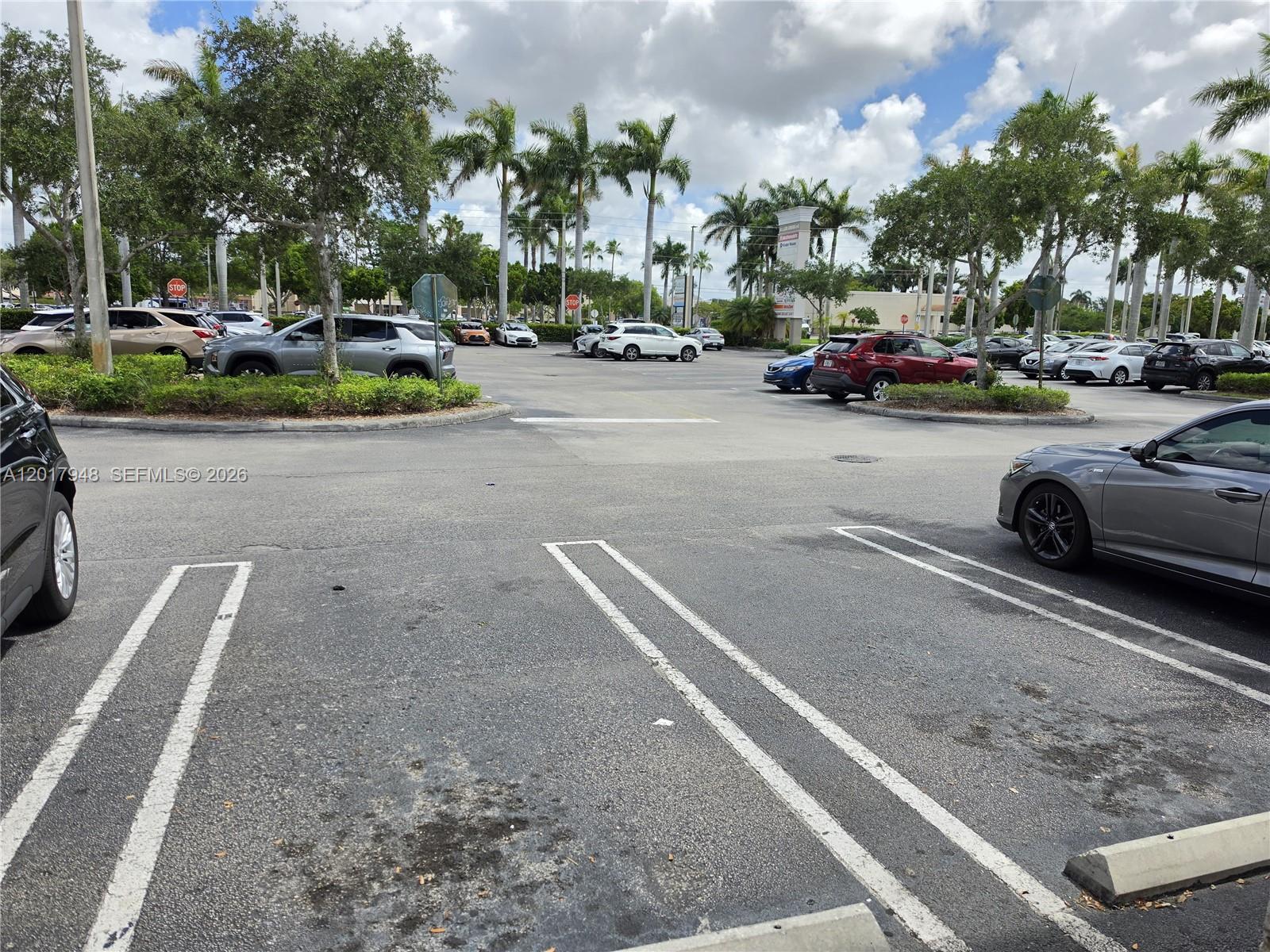 A parking lot features numerous parked vehicles, palm trees, and a blue sky with clouds — 15750 SW 56 ST, Miami FL 33185, MIAMI, FL