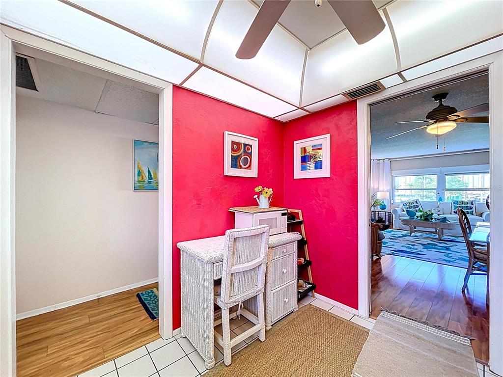 A bright pink wall features a white wicker desk and chair in a tiled room — 4650 COVE CIRCLE UNIT 209, ST PETERSBURG, FL