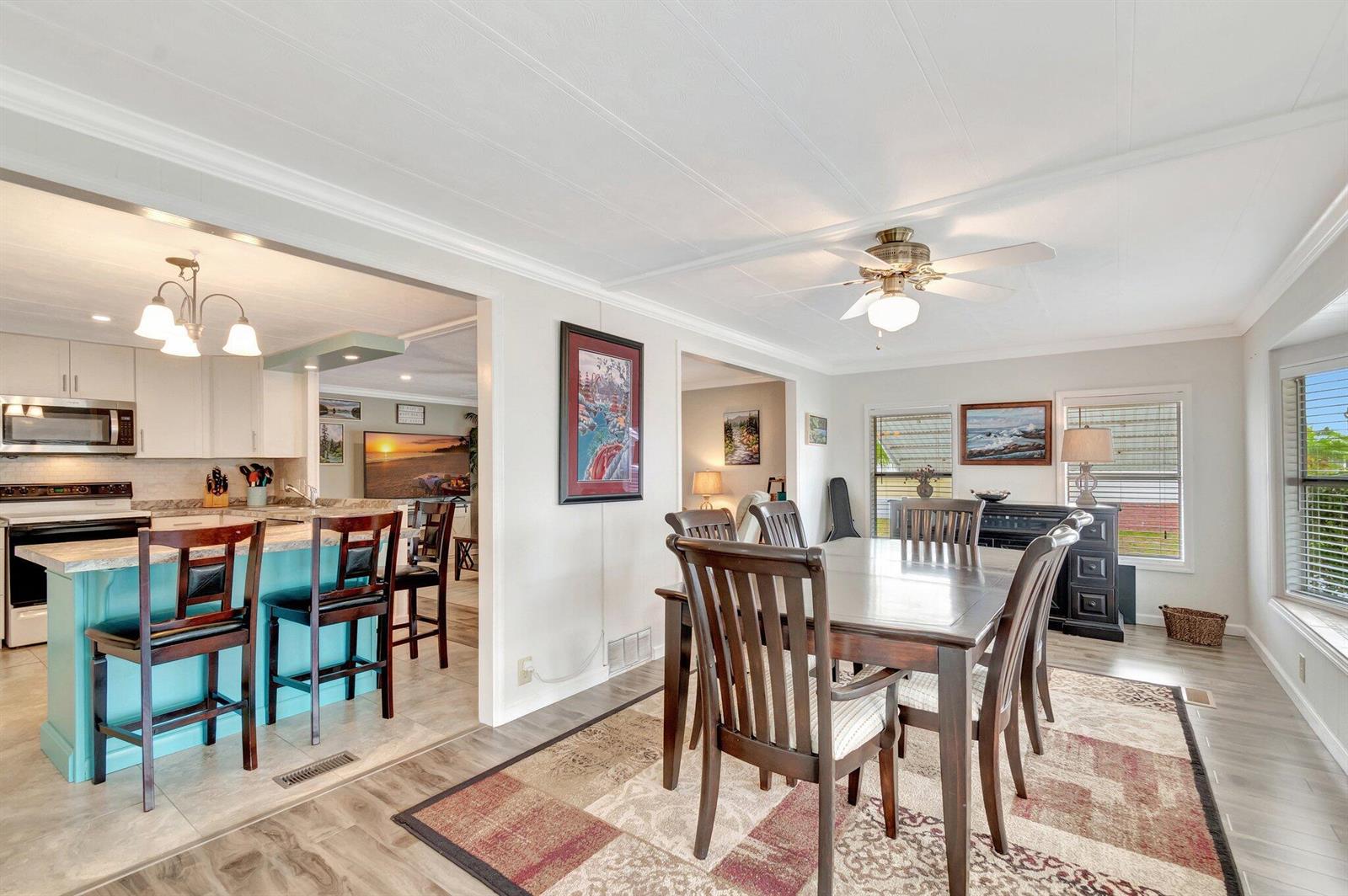 A dining area with a wooden table and chairs sits adjacent to a turquoise kitchen island — 14001 Kingston Bay, Boynton Beach FL 33436, BOYNTON BEACH, FL