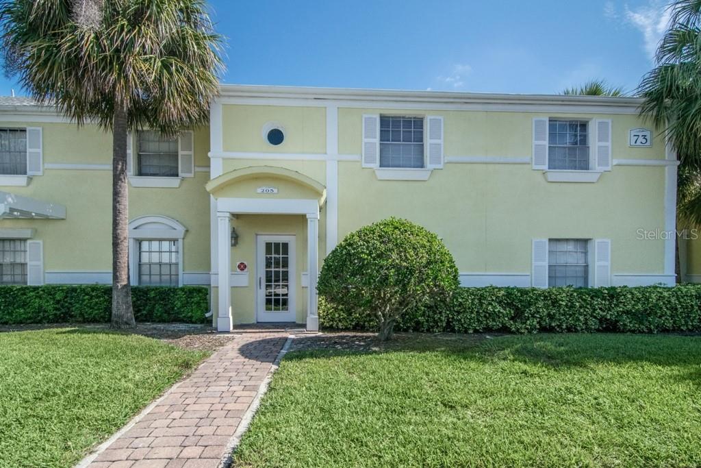 A two-story yellow building with a brick walkway leading to a central front entrance — 205 POMPANO DRIVE SE UNIT D, ST PETERSBURG, FL
