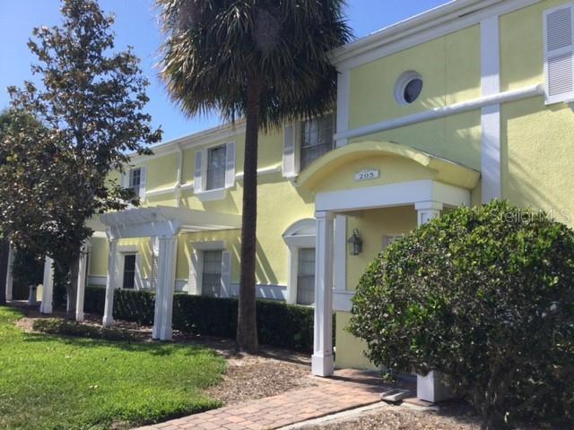 A yellow two-story building features a white arched entryway, a pergola, and a palm tree — 205 POMPANO DRIVE SE UNIT D, ST PETERSBURG, FL