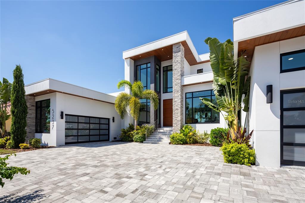 A modern two-story house with a stone pillar, glass garage doors, and a paved driveway — 5237 61ST AVENUE S, ST PETERSBURG, FL