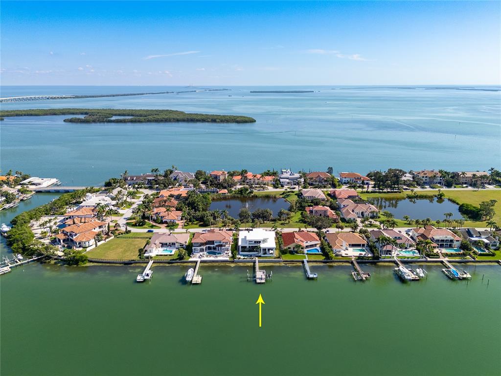 An aerial view of a waterfront neighborhood with a modern white house highlighted by an arrow — 5237 61ST AVENUE S, ST PETERSBURG, FL