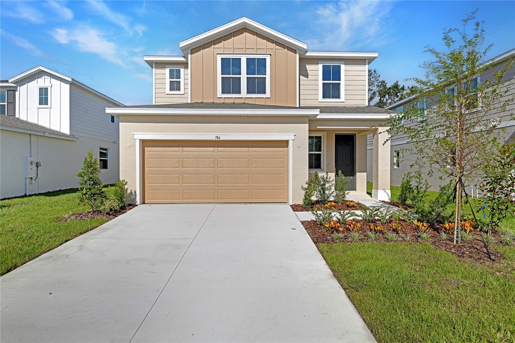 A two-story suburban house features a tan stucco exterior, a two-car garage, and a driveway — 746 LAKE DELL AVENUE, DUNDEE, FL