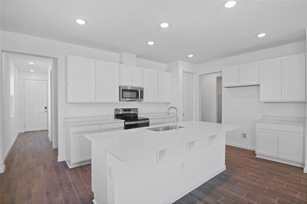 A modern kitchen features white cabinetry, a large central island, and wood-look tile flooring — 746 LAKE DELL AVENUE, DUNDEE, FL