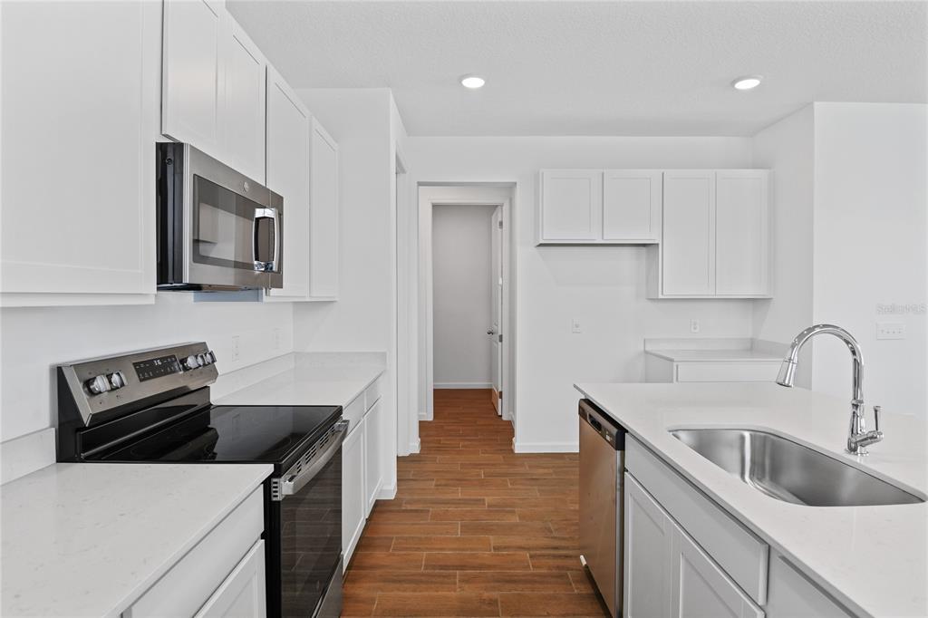 A modern kitchen features white cabinets, stainless steel appliances, a kitchen island, and wood-look flooring — 746 LAKE DELL AVENUE, DUNDEE, FL
