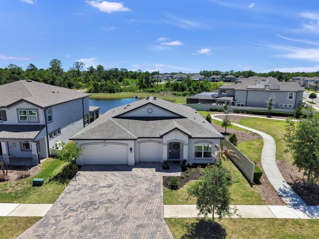 An aerial view shows a single-story house with a paver driveway and a backyard pond — 12048 ORCHID ASH STREET, RIVERVIEW, FL