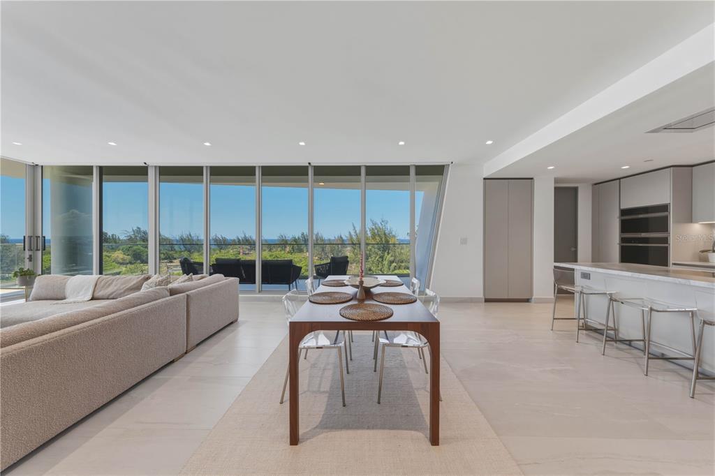 An open-concept living and dining area features floor-to-ceiling windows with ocean views and tile flooring — 540 AVE. DE LA CONSTITUCION UNIT 801, SAN JUAN, PR