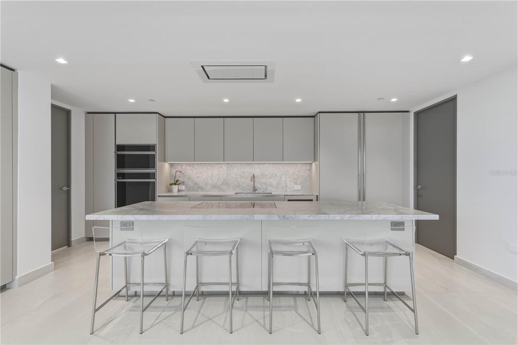 A modern kitchen features a marble island, light gray cabinetry, and four clear acrylic stools — 540 AVE. DE LA CONSTITUCION UNIT 801, SAN JUAN, PR