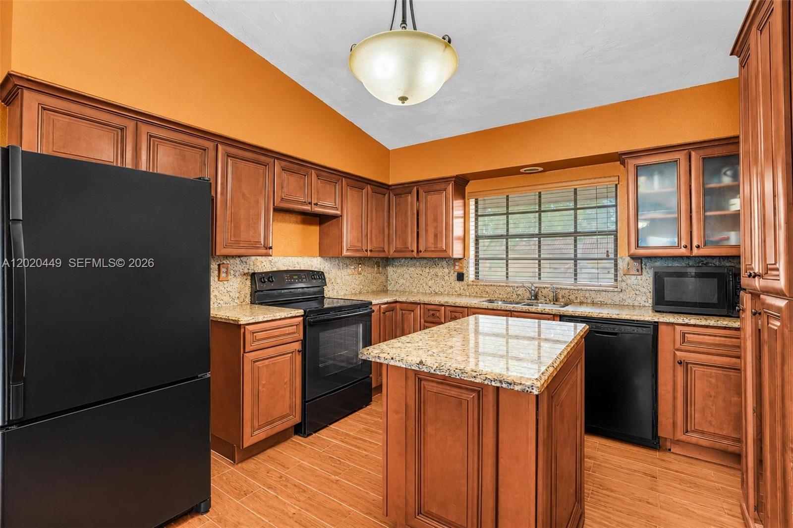 A kitchen features wood cabinets, granite countertops, black appliances, and an island — 11061 SW 163rd St, Miami FL 33157, MIAMI, FL