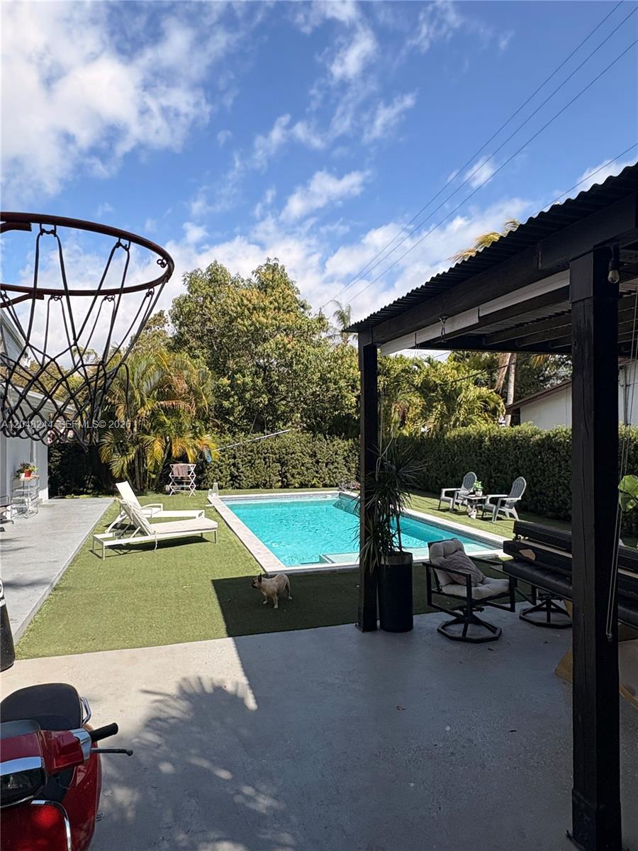 A backyard features a swimming pool, artificial turf, a basketball hoop, and a covered patio — 12125 NE 2nd Ave, North Miami FL 33161, NORTH MIAMI, FL