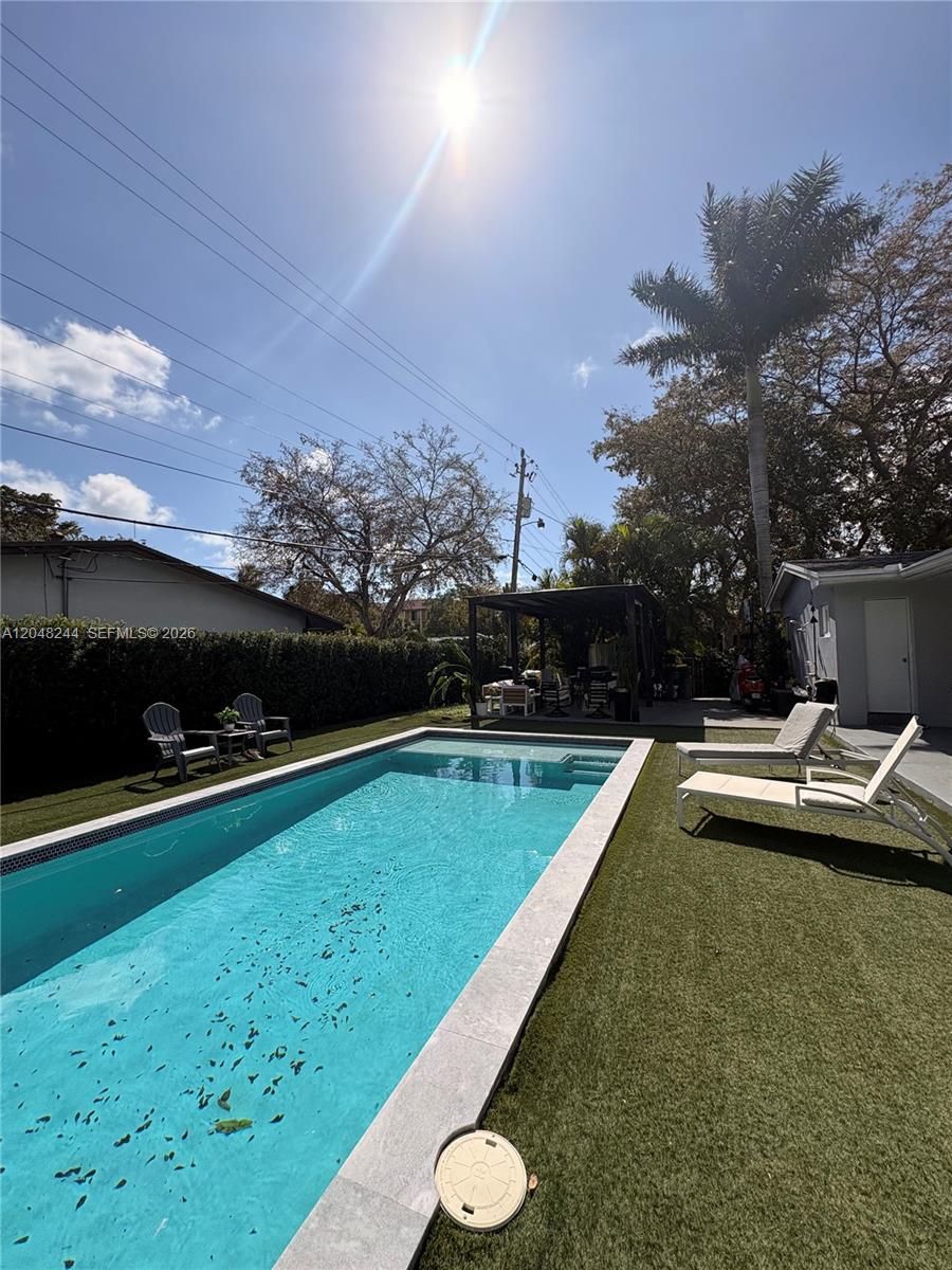 A rectangular swimming pool sits in a backyard with artificial turf and lounge chairs — 12125 NE 2nd Ave, North Miami FL 33161, NORTH MIAMI, FL