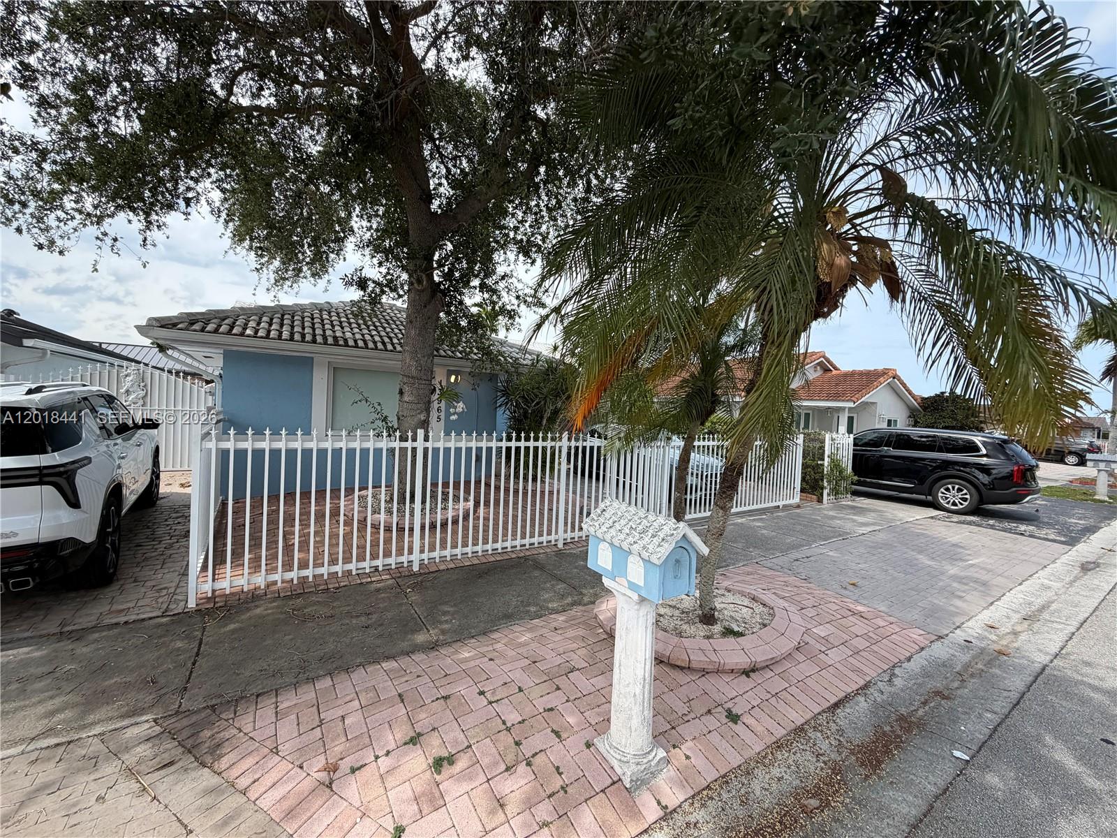 A blue house with a white fence and a decorative mailbox stands behind a palm tree — 13965 SW 10th St, Miami FL 33184, MIAMI, FL