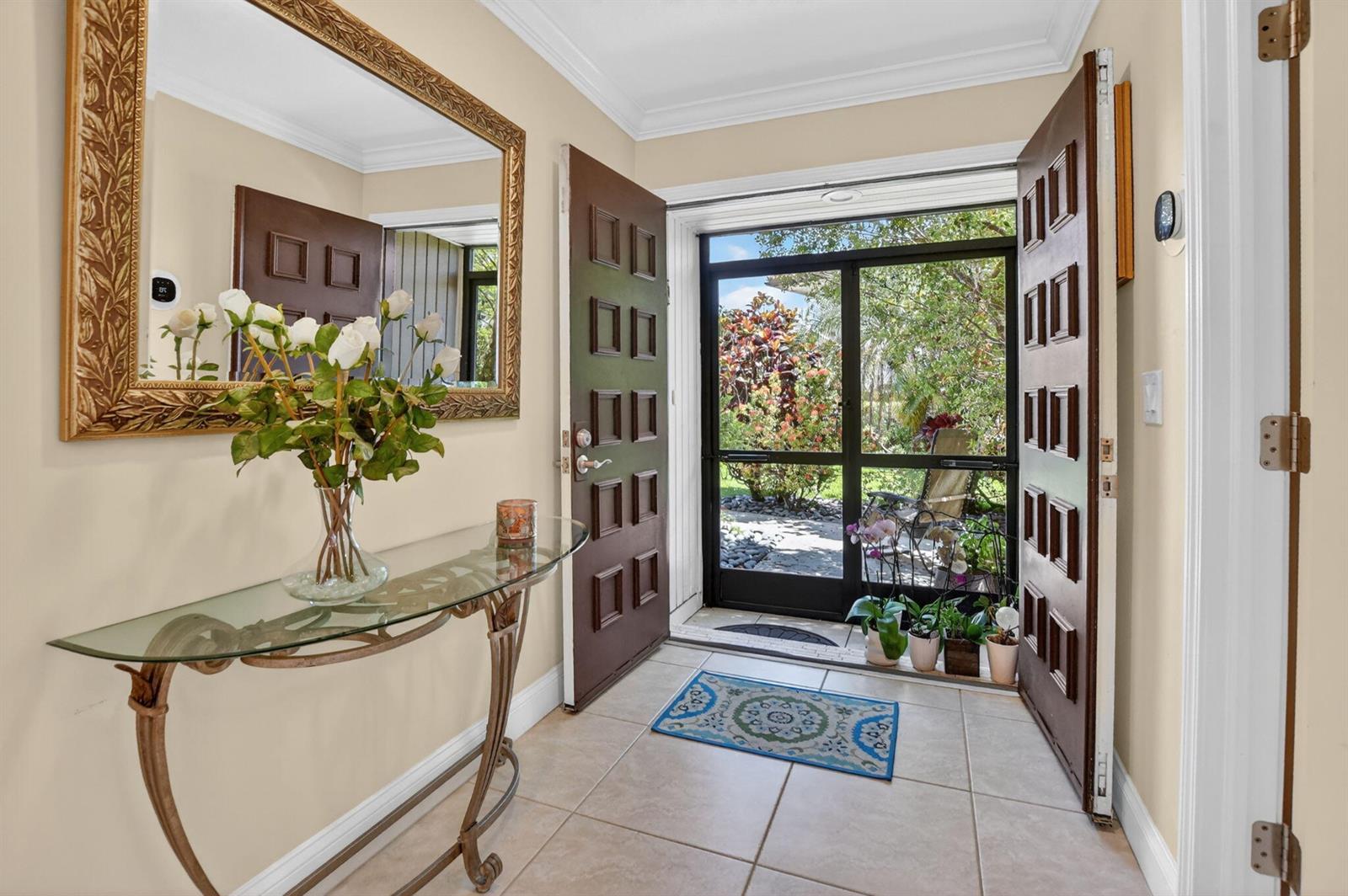 An entryway features a glass console table, a large mirror, and open double doors — 8208 Casa Del Lago # 23b, Boca Raton FL 33433, BOCA RATON, FL