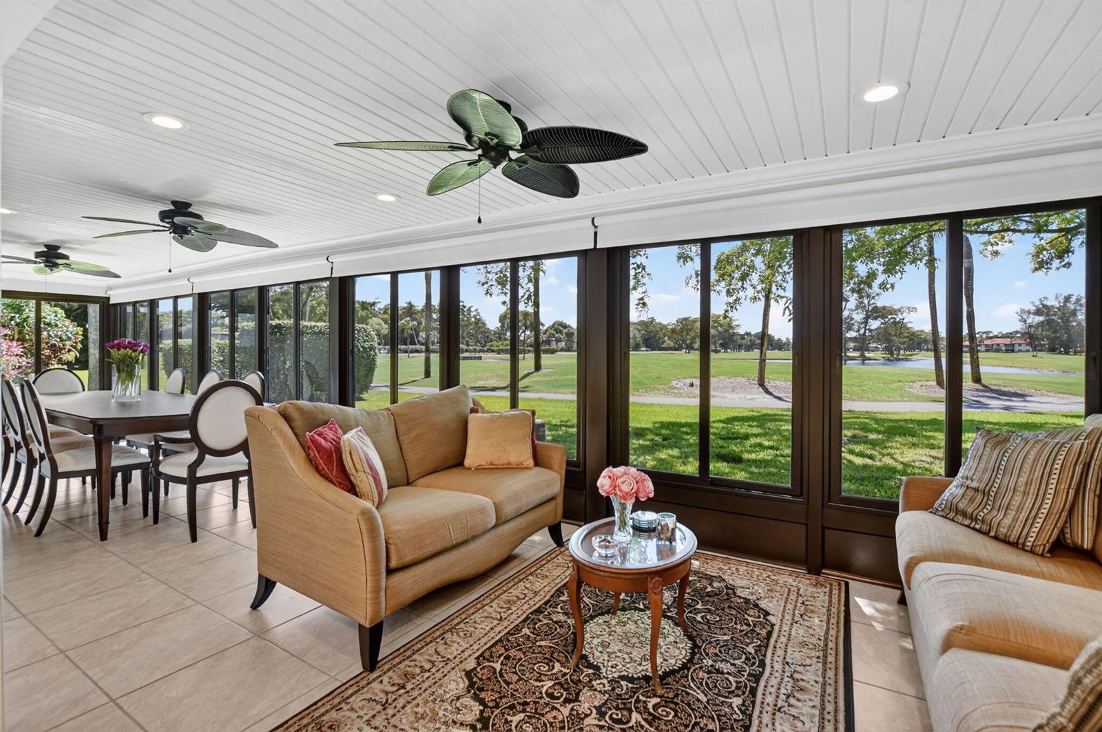 A sunroom features tile floors, two ceiling fans, and large windows overlooking a golf course — 8208 Casa Del Lago # 23b, Boca Raton FL 33433, BOCA RATON, FL