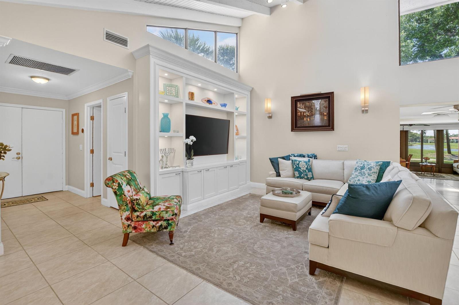 A living room features a white built-in entertainment center, a sectional sofa, and floral armchair — 8208 Casa Del Lago # 23b, Boca Raton FL 33433, BOCA RATON, FL