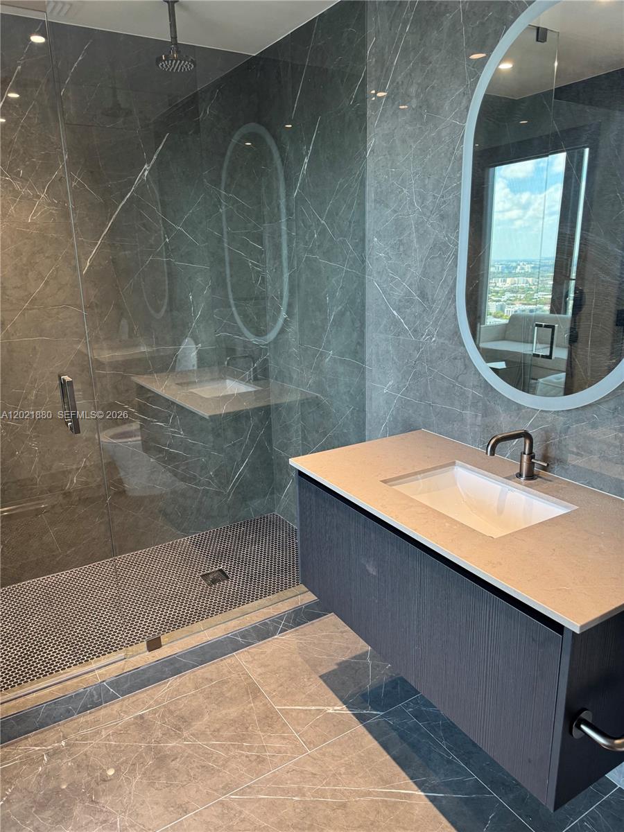 A modern bathroom features a glass-enclosed shower, a floating vanity, and gray marble-style tiling — 20 NE 11th St # 3405, Miami FL 33132, MIAMI, FL