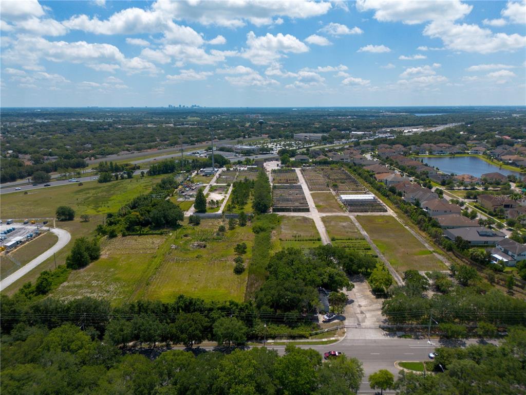 An aerial view shows a large, partially developed plot of land with greenhouses and nearby houses — 1955 S APOPKA VINELAND ROAD, ORLANDO, FL