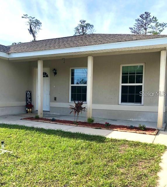 The exterior of a single-story house features a covered front porch and a small garden bed — 16718 SW 21ST CIRCLE, OCALA, FL