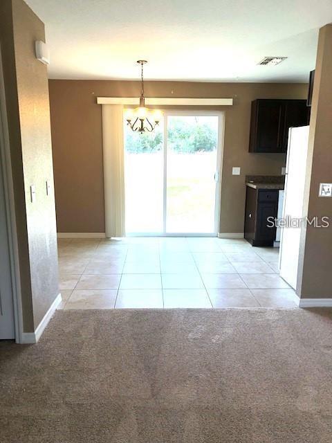A dining area with tile flooring features a sliding glass door and a hanging chandelier — 16718 SW 21ST CIRCLE, OCALA, FL