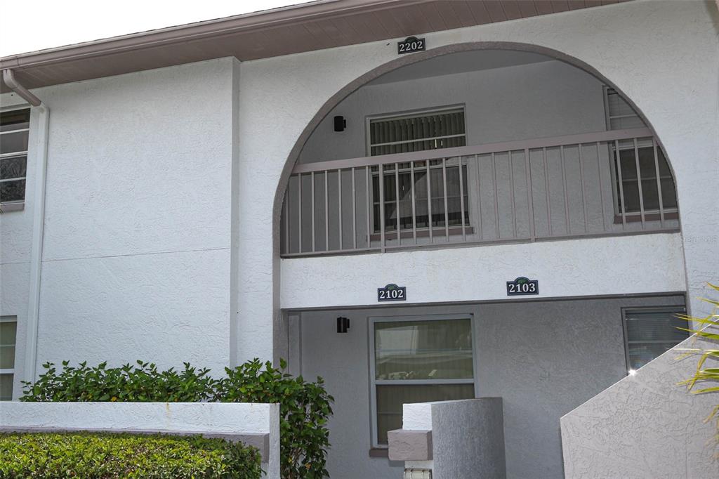 An exterior view of a two-story apartment building with a balcony and arched entryway — 3203 LANDMARK DRIVE UNIT 2202, CLEARWATER, FL