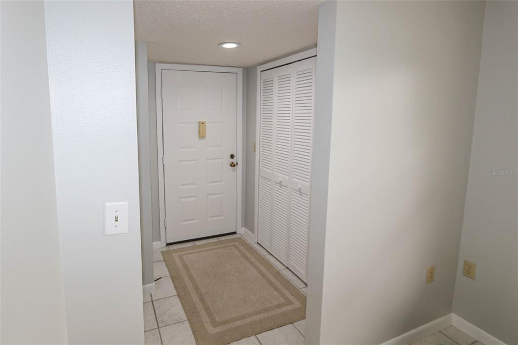 An entryway features a white front door, a louvered closet, and tile flooring — 3203 LANDMARK DRIVE UNIT 2202, CLEARWATER, FL
