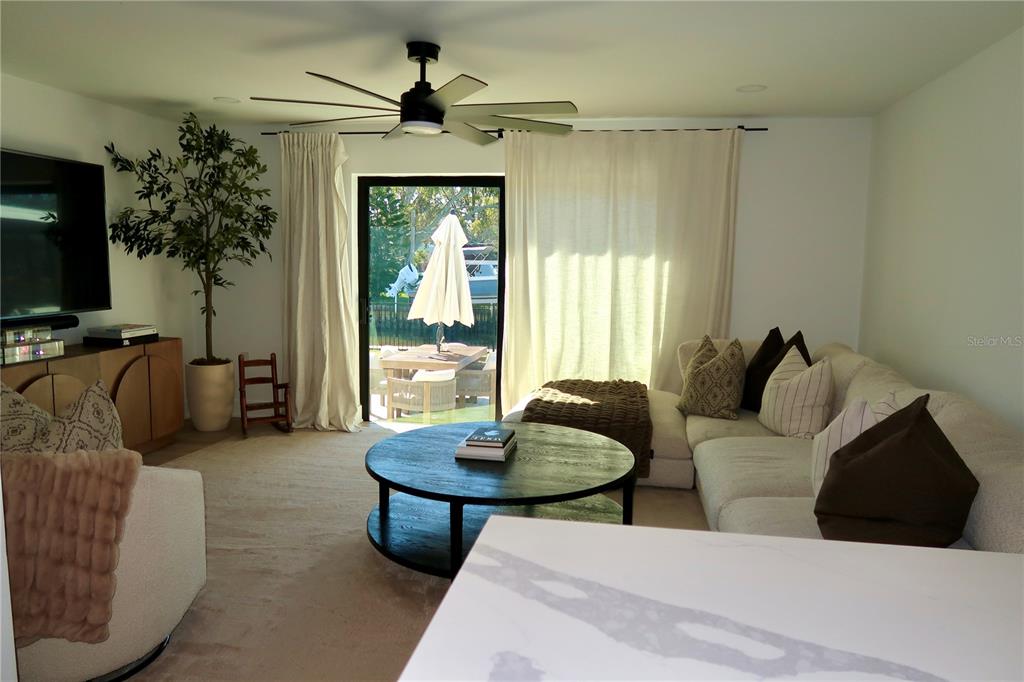 A living room features a sectional sofa, round coffee table, and sliding glass doors — 9484 TREASURE LANE NE, ST PETERSBURG, FL