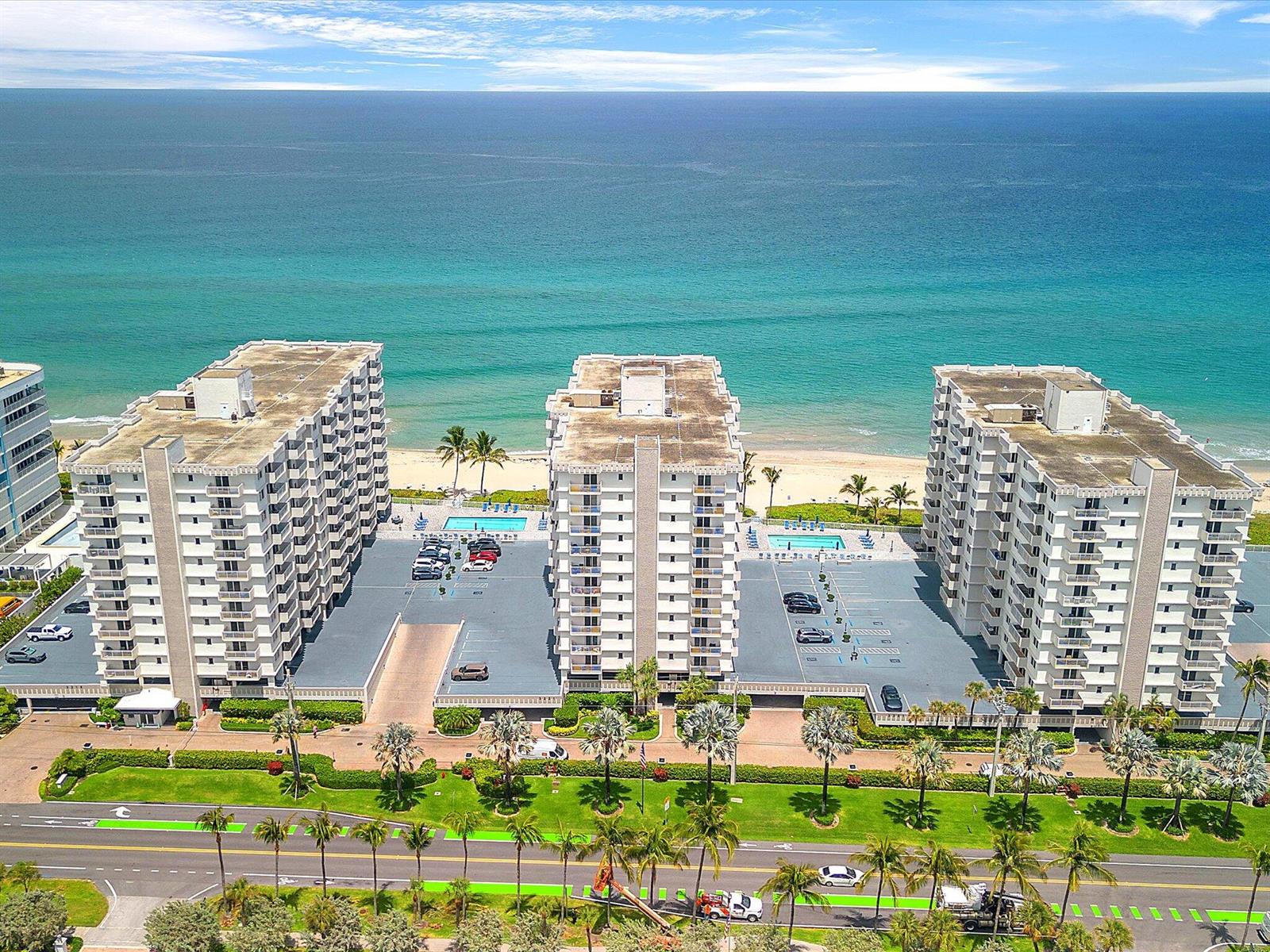 An aerial view shows three beachfront apartment buildings with parking lots and swimming pools — 3215 S Ocean Boulevard # 104, Highland Beach FL 33487, HIGHLAND BEACH, FL