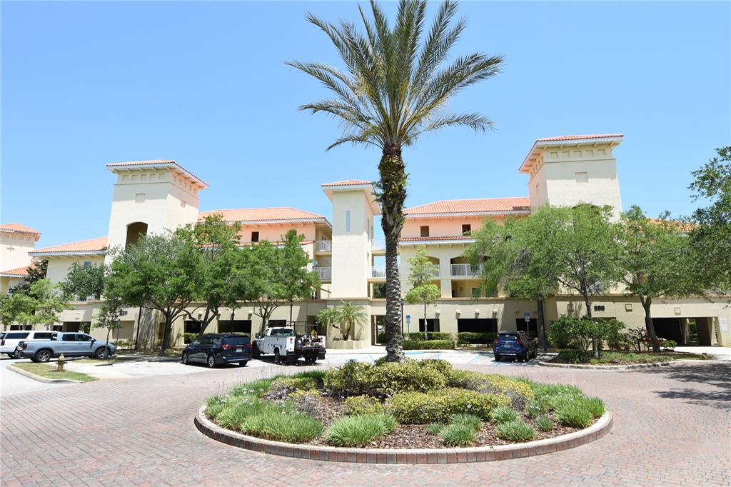 A multi-story apartment building with a central palm tree and a circular driveway — 100 BELLA HARBOR COURT UNIT 111, PALM COAST, FL
