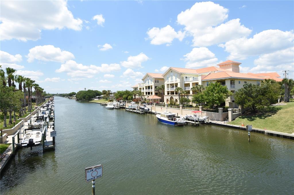 A canal lined with docked boats runs alongside a large multi-story residential building — 100 BELLA HARBOR COURT UNIT 111, PALM COAST, FL