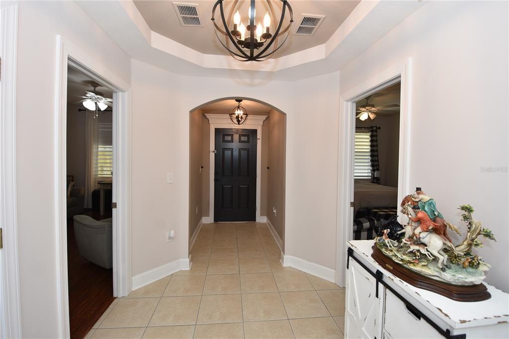 A tiled entryway features a tray ceiling with a chandelier and a dark front door — 100 BELLA HARBOR COURT UNIT 111, PALM COAST, FL