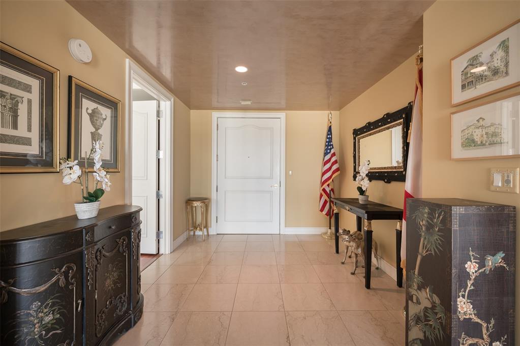 A tiled entryway features a white door, two dark console tables, and decorative wall art — 1111 RITZ CARLTON DRIVE UNIT 1205, SARASOTA, FL