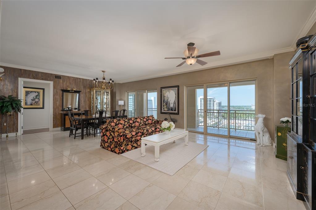 A spacious living and dining room with tile floors, a floral sofa, and balcony views — 1111 RITZ CARLTON DRIVE UNIT 1205, SARASOTA, FL