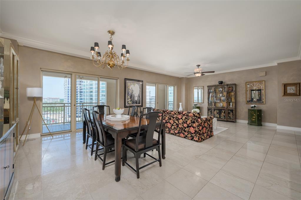 A dining and living area features tile floors, a floral sofa, and a glass balcony door — 1111 RITZ CARLTON DRIVE UNIT 1205, SARASOTA, FL