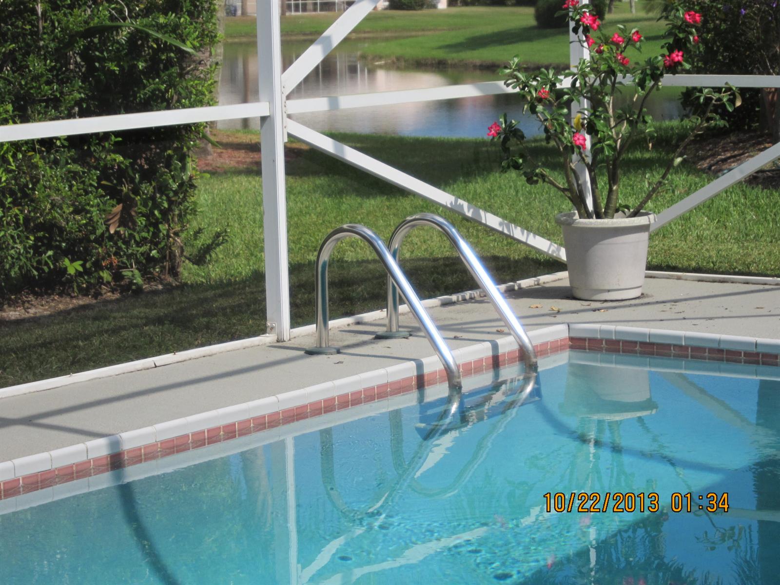 A swimming pool with metal handrails sits on a patio enclosed by a white screen — 6325 Winding Lake Drive, Jupiter FL 33458, JUPITER, FL