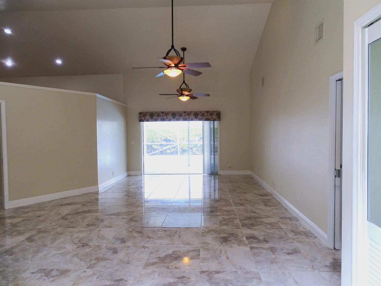 A spacious room with vaulted ceilings, two ceiling fans, and light-colored tile flooring — 6325 Winding Lake Drive, Jupiter FL 33458, JUPITER, FL