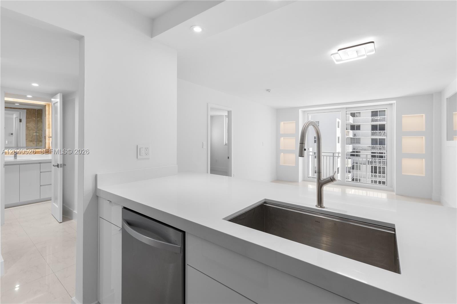 A modern kitchen features white countertops, a stainless steel sink, and a view of balconies — 345 Ocean Dr # 924, Miami Beach FL 33139, MIAMI BEACH, FL