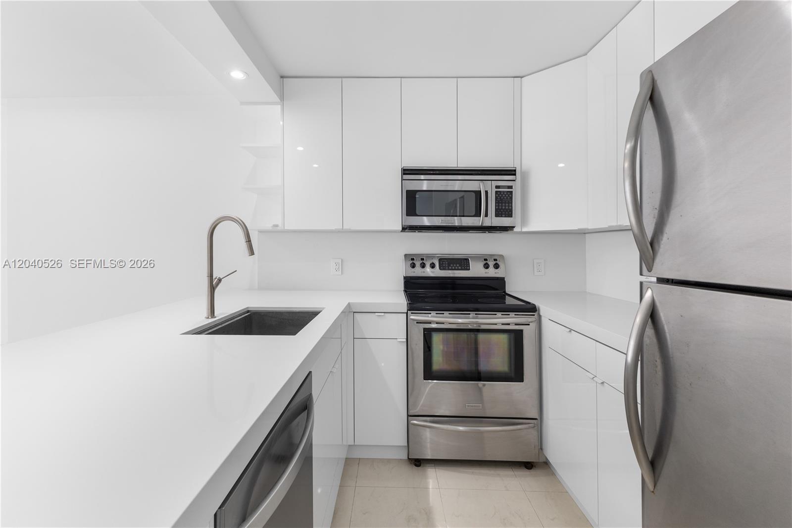 A modern kitchen features white cabinets, stainless steel appliances, and white countertops — 345 Ocean Dr # 924, Miami Beach FL 33139, MIAMI BEACH, FL