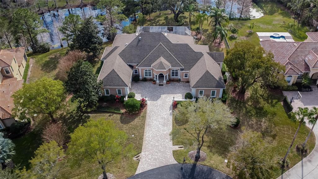 An aerial view shows a large house with a paved driveway and a backyard pool — 8510 KENTUCKY DERBY DRIVE, ODESSA, FL