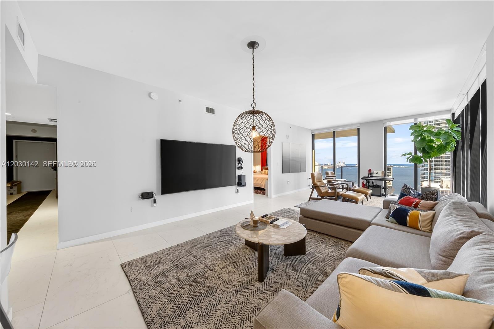 A modern living room features a large sectional sofa, a round coffee table, and floor-to-ceiling windows — 1010 Brickell Ave # 2905, Miami FL 33131, MIAMI, FL