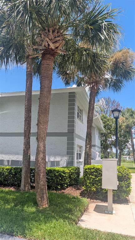 A two-story building with gray trim and palm trees stands next to a sidewalk — 458 FAIRWAYS CIRCLE UNIT 201, OCALA, FL