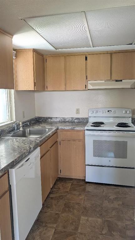 A kitchen features light wood cabinets, a white stove, a dishwasher, and a laminate countertop — 458 FAIRWAYS CIRCLE UNIT 201, OCALA, FL