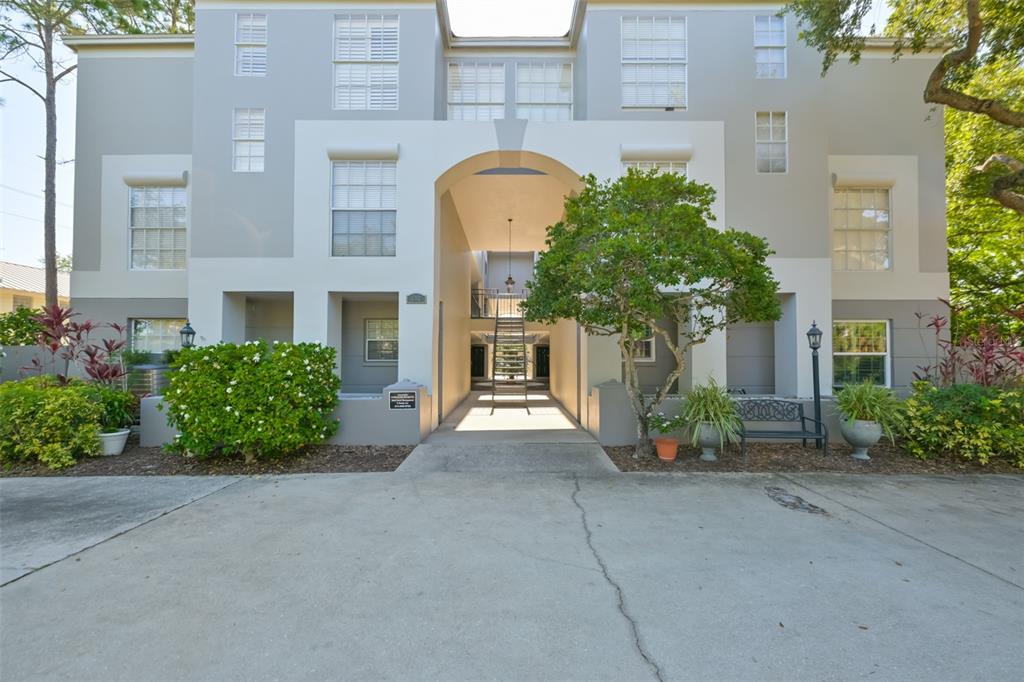 A three-story apartment building features a central arched entryway with stairs and surrounding landscaping — 606 S GLEN AVENUE UNIT 10, TAMPA, FL