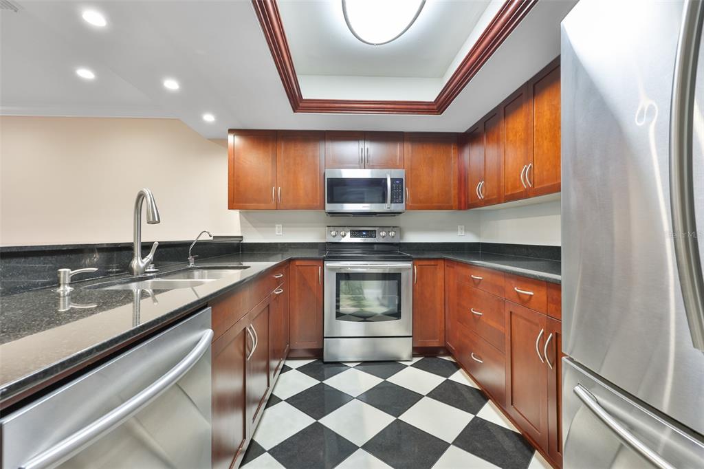 A kitchen features cherry wood cabinets, black granite countertops, stainless steel appliances, and checkered flooring — 606 S GLEN AVENUE UNIT 10, TAMPA, FL