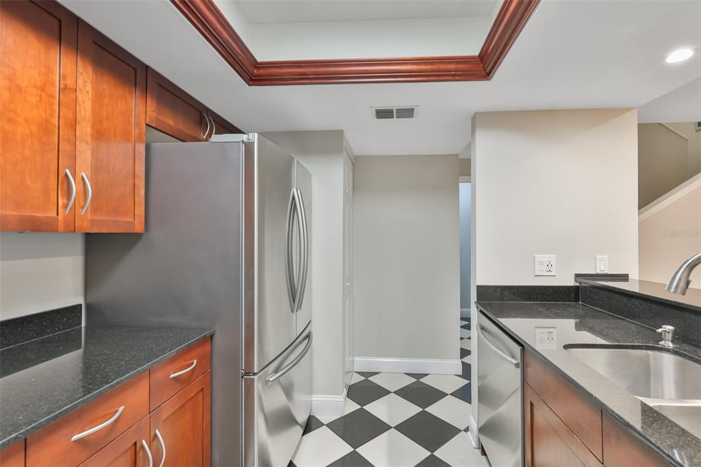 A kitchen features wood cabinets, black granite countertops, stainless steel appliances, and checkered floor tiles — 606 S GLEN AVENUE UNIT 10, TAMPA, FL