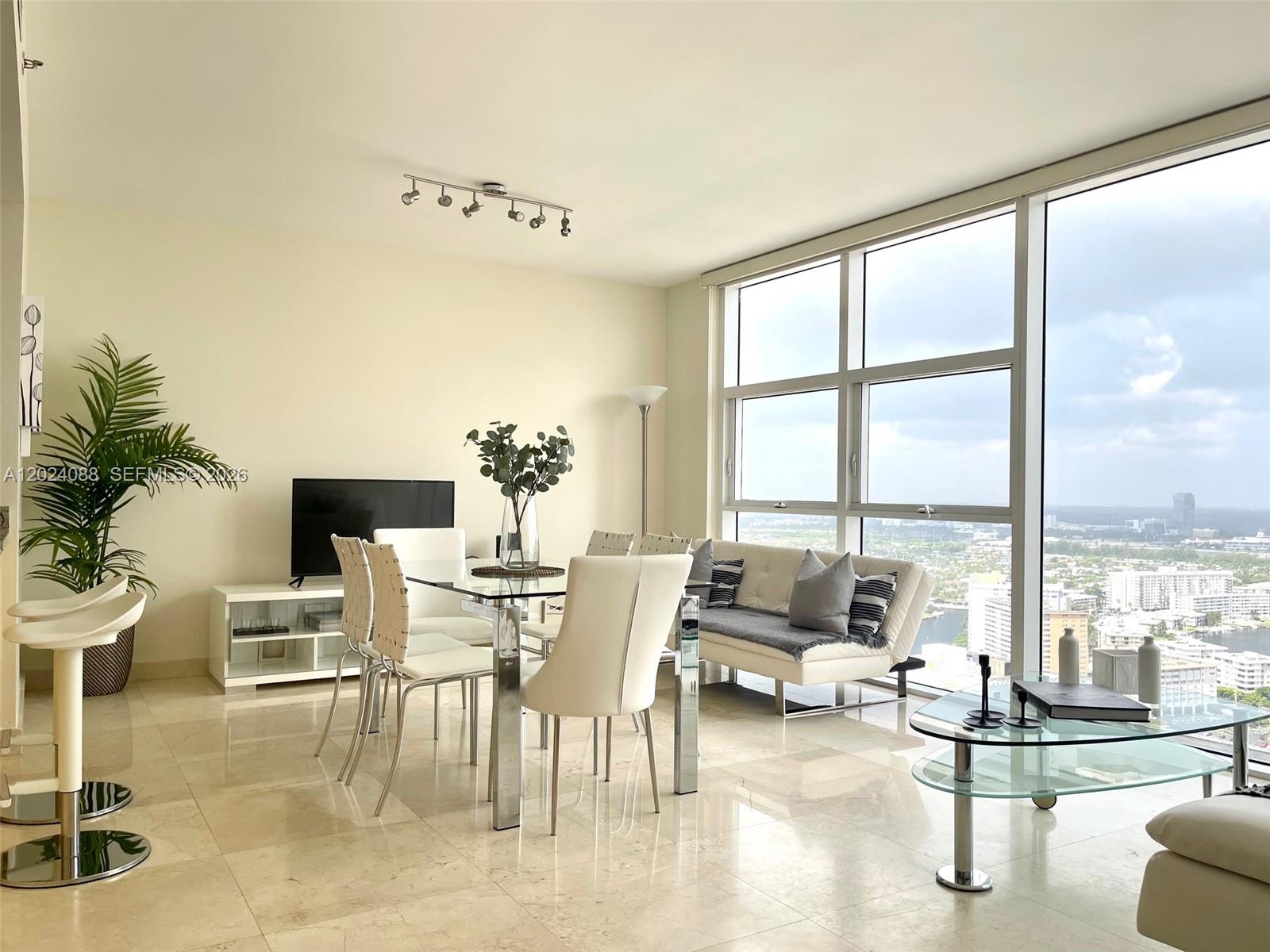 A bright living and dining area features floor-to-ceiling windows with expansive city views — 1830 S Ocean Dr # 3407, Hallandale Beach FL 33009, HALLANDALE BEACH, FL