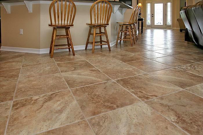 A kitchen island with three wooden bar stools sits on a diagonal tile floor — 1195 LATTIMORE DRIVE, CLERMONT, FL