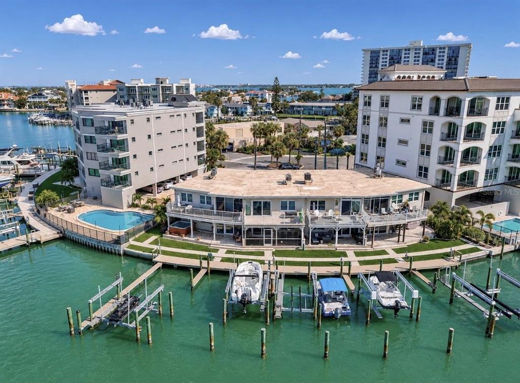 An aerial view of a waterfront apartment complex featuring boat slips and a swimming pool — 205 DOLPHIN POINT UNIT 4, CLEARWATER BEACH, FL